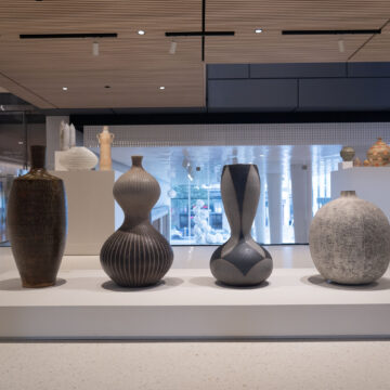 Four ceramic artworks staged in an exhibition hall with smaller pieces on display in the backround