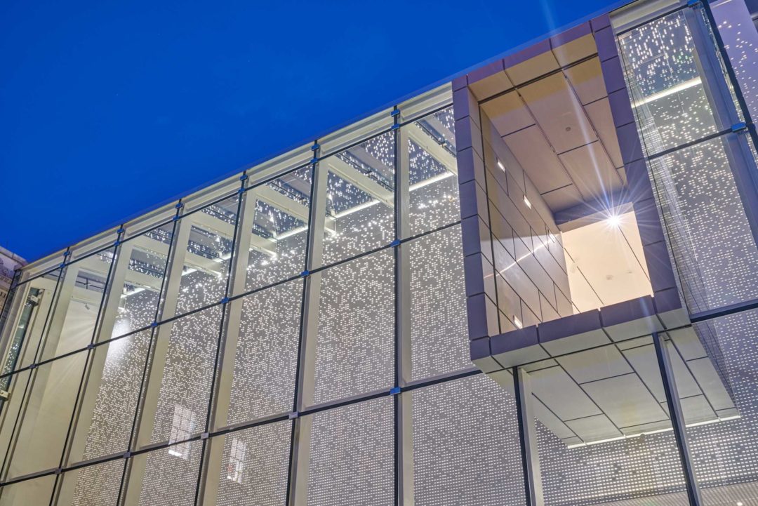 Image of the Asheville Art Museum lit up at night.